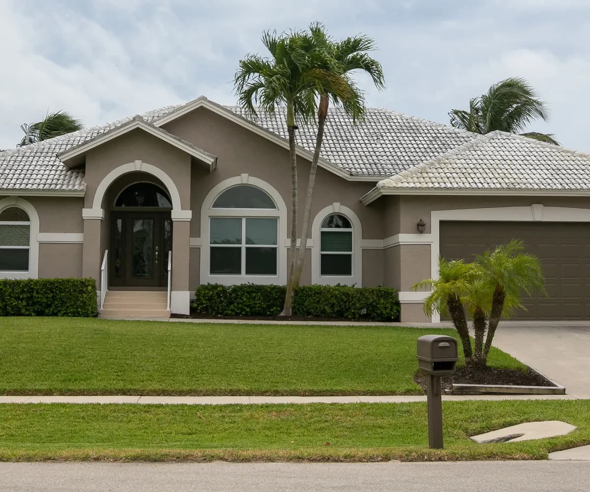 Stucco ranch home with a tile roof and a palm tree