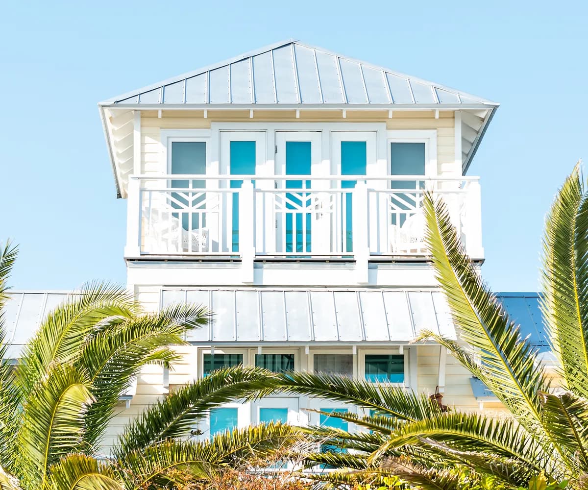 Coastal home with standing seam metal roofs behind palms
