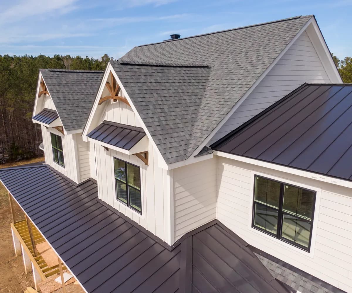 Farmhouse-style home with a shingle roof and metal porch roofs