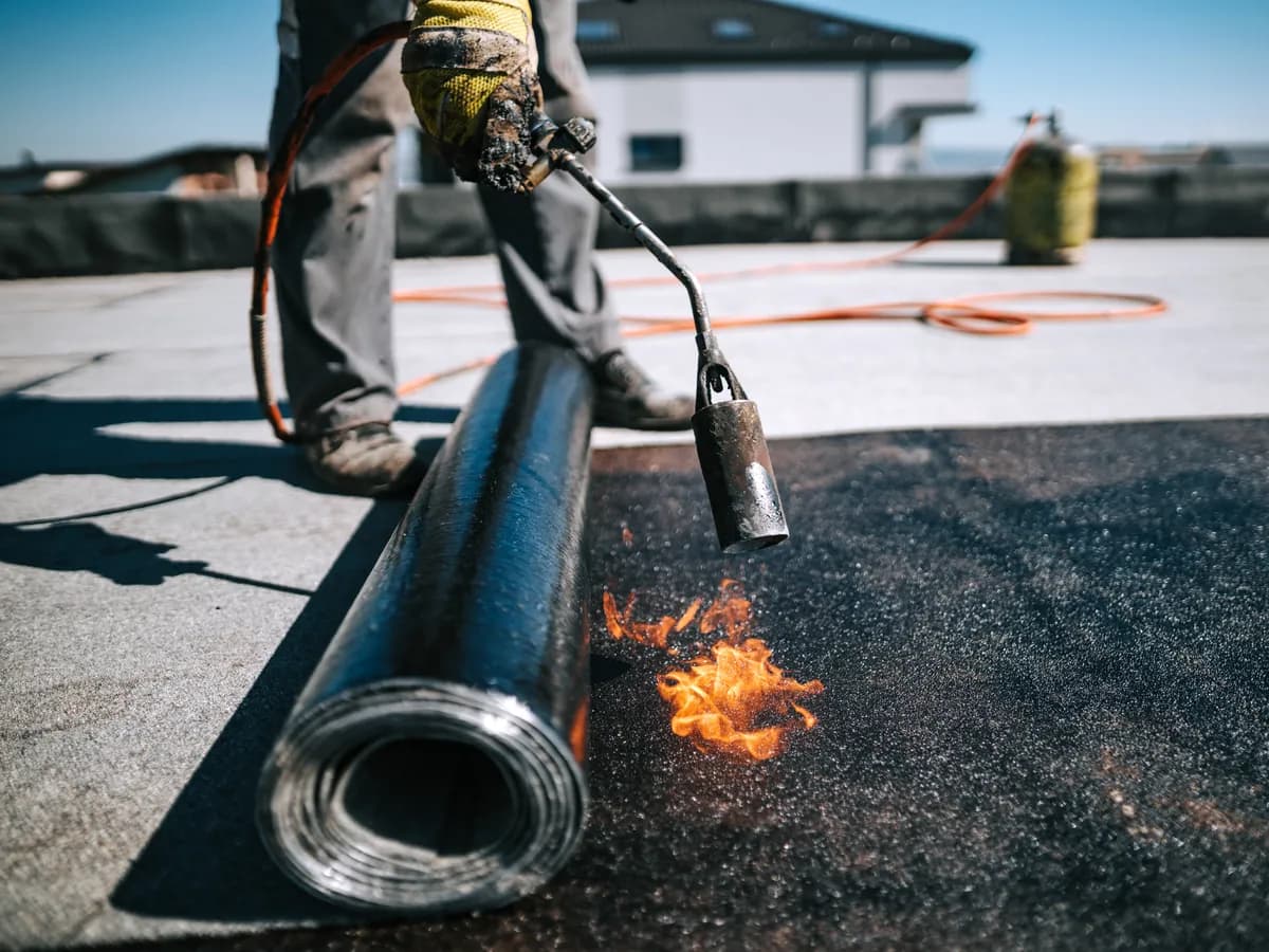 Roofer torch-applying a modified bitumen roll