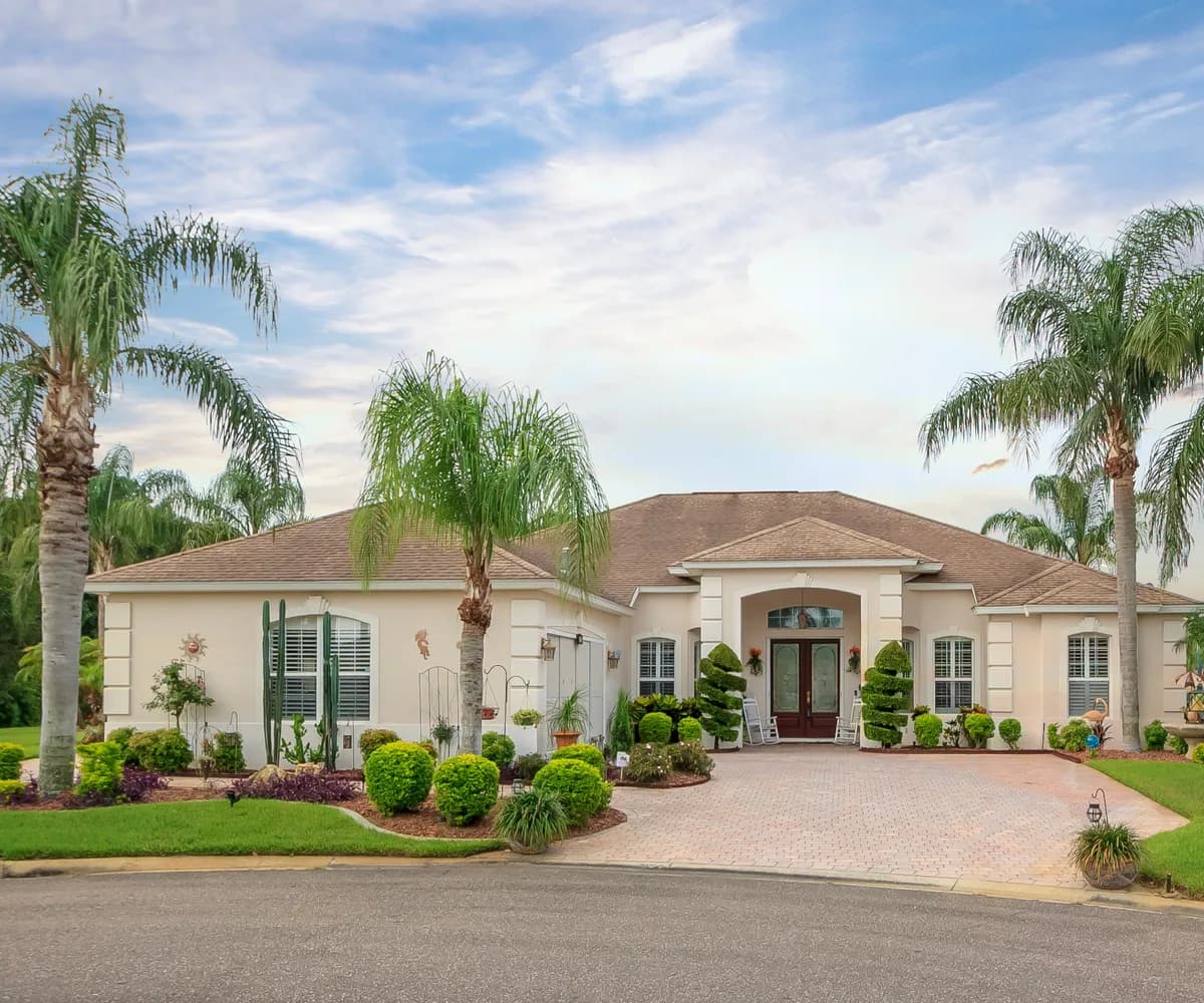 Stucco ranch home with an architectural shingle roof on a palm-lined cul-de-sac