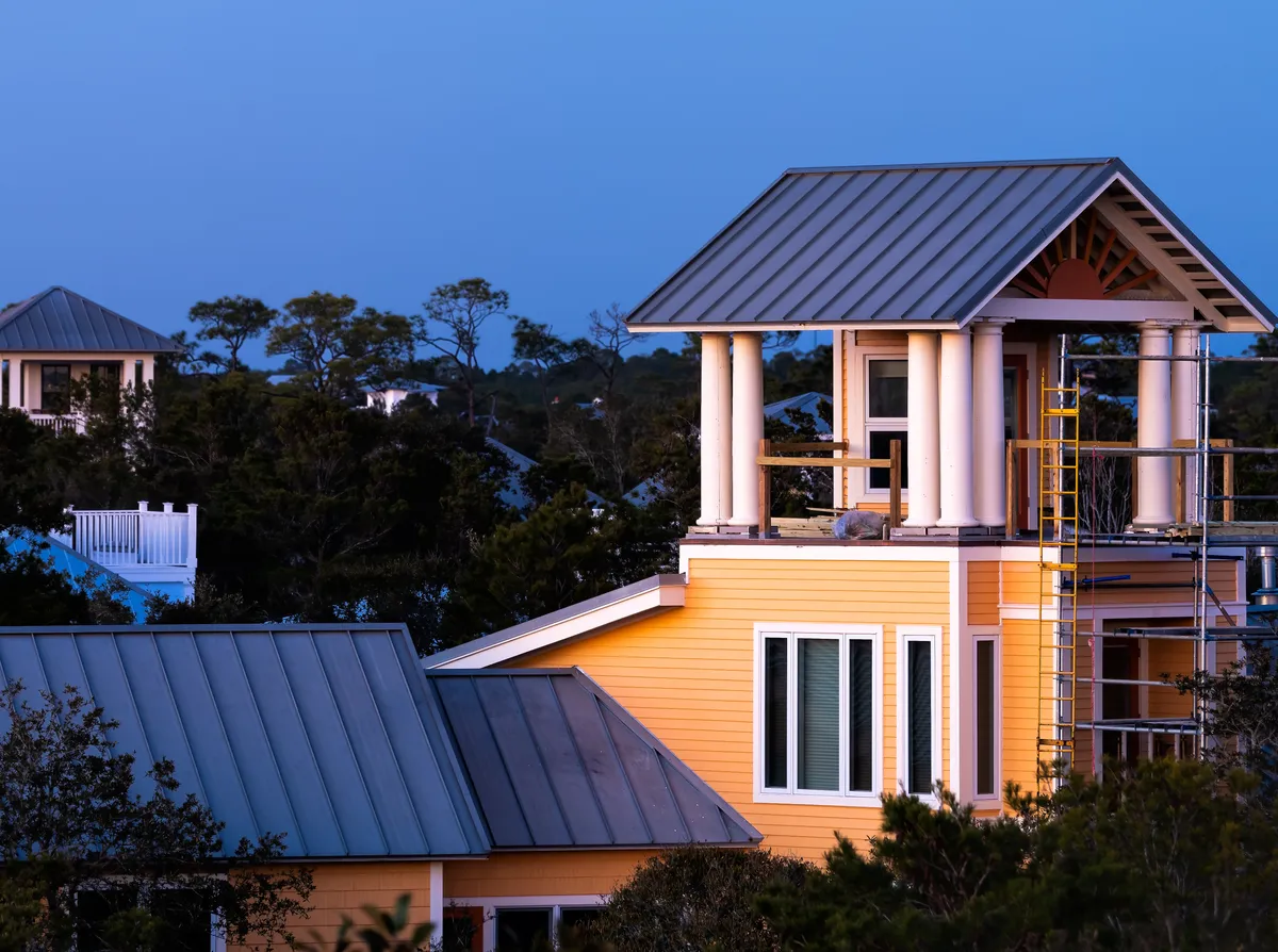Coastal homes with standing seam metal roofs and a lookout tower at dusk