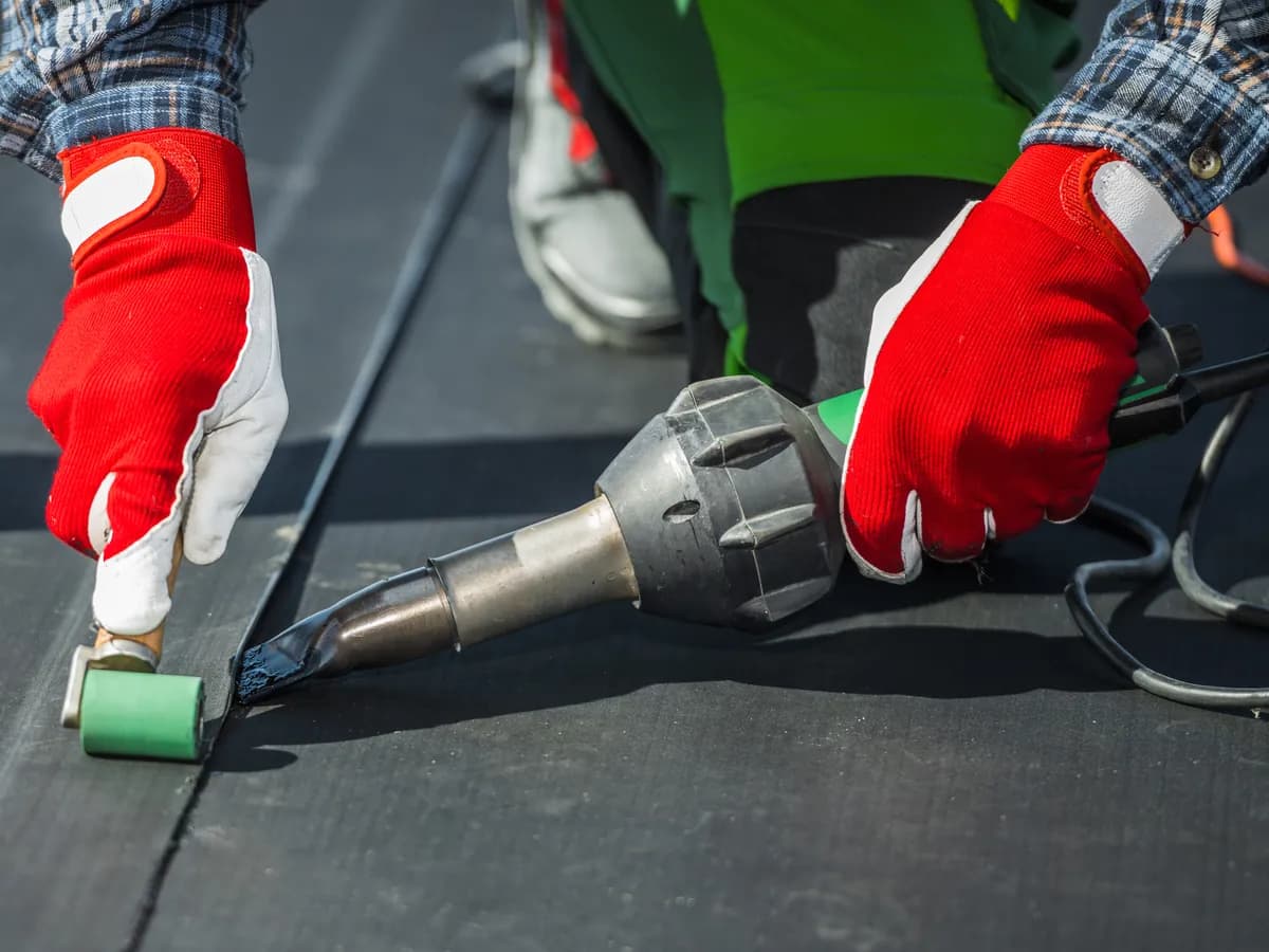 Roofers heat-welding a membrane seam