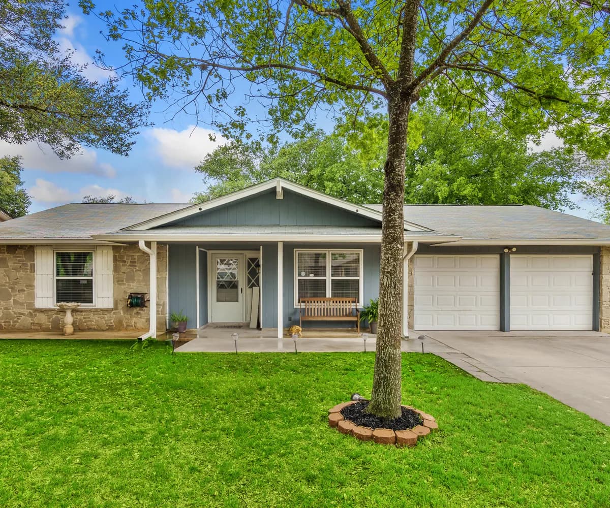 Single-story ranch home with a shingle roof and a shade tree