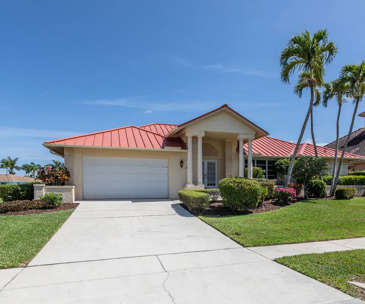 Home with a red metal roof and palm trees