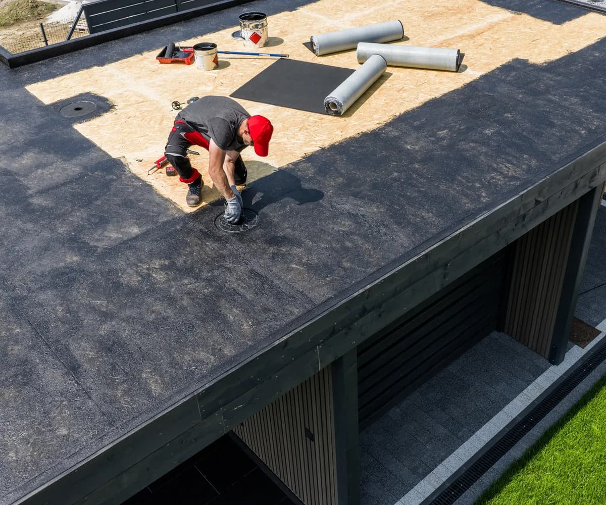 Roofer installing a membrane on the flat roof of a modern home