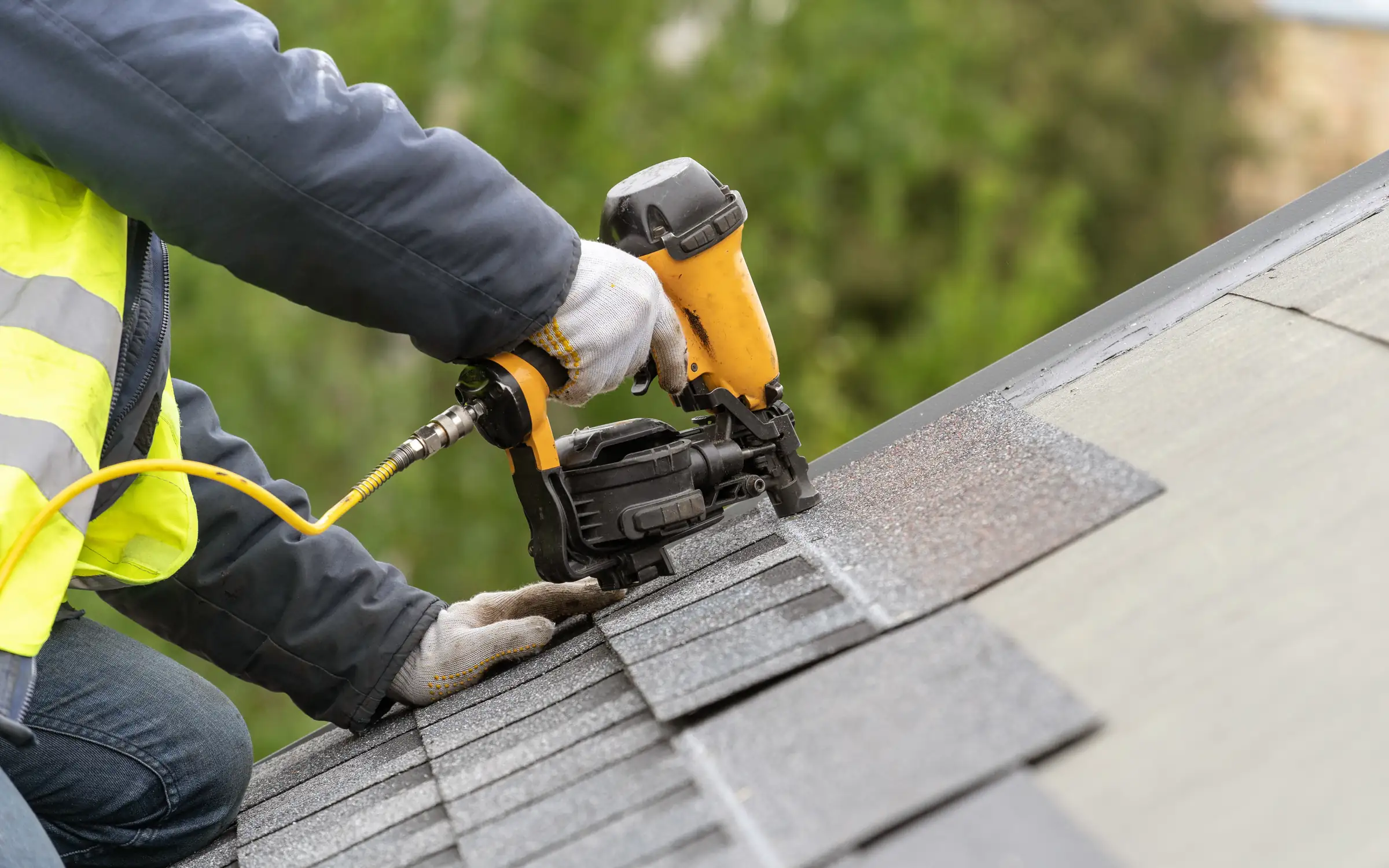 Roofer installing shingles with a nail gun