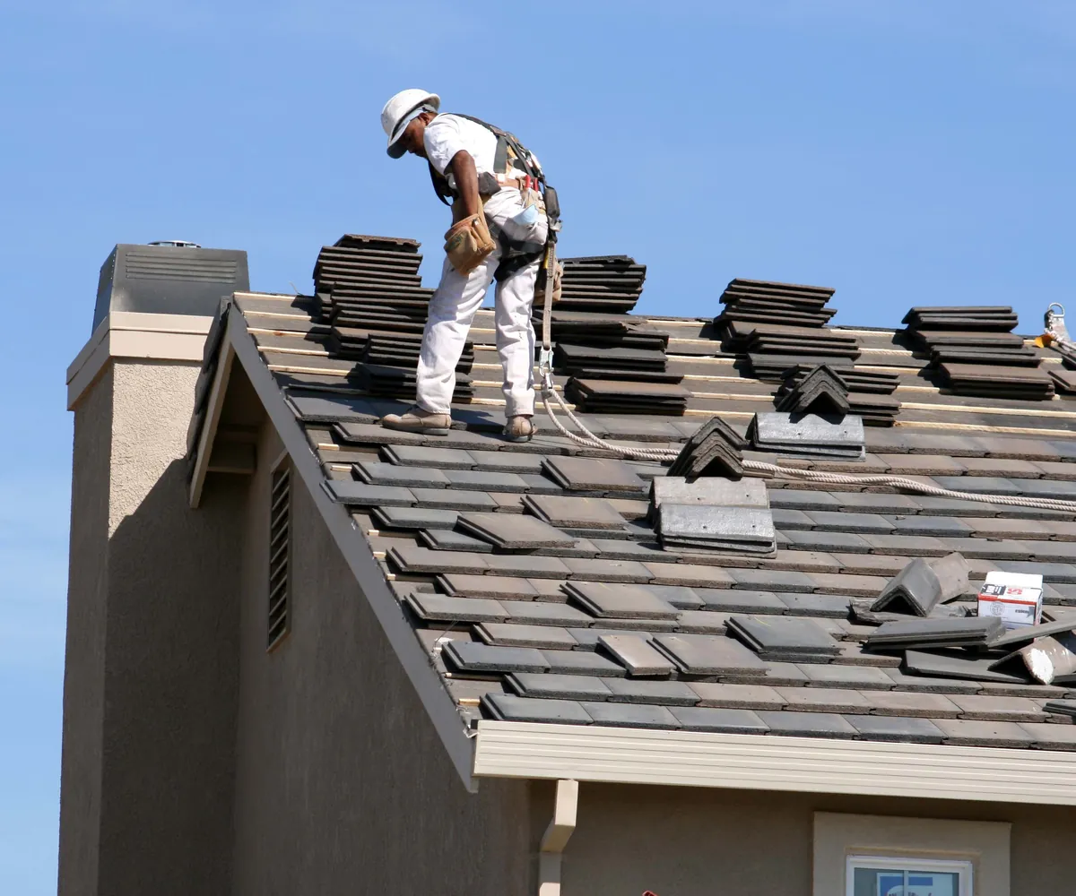 Roofer setting concrete tile on a stucco home