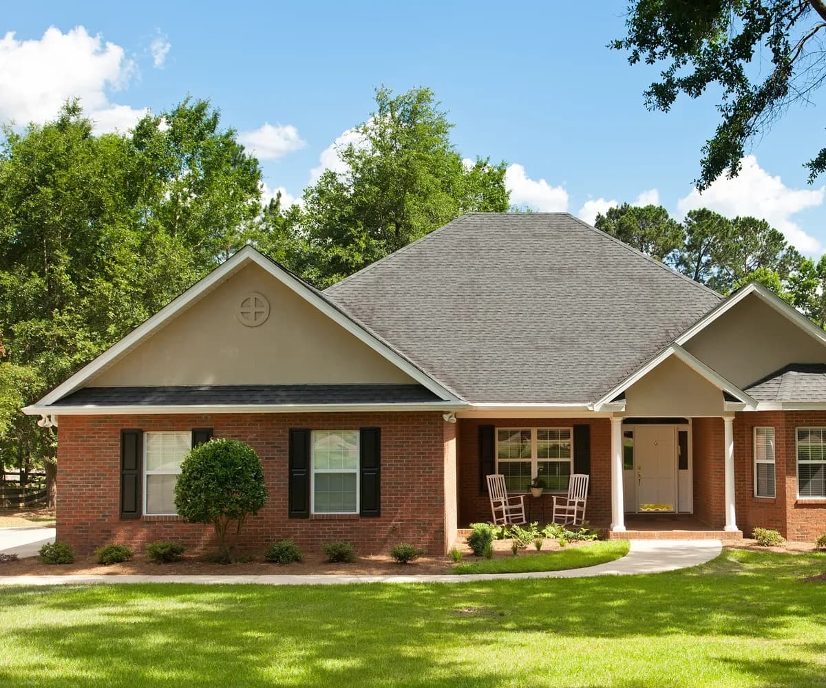 Brick ranch home with an architectural shingle roof and a shade tree