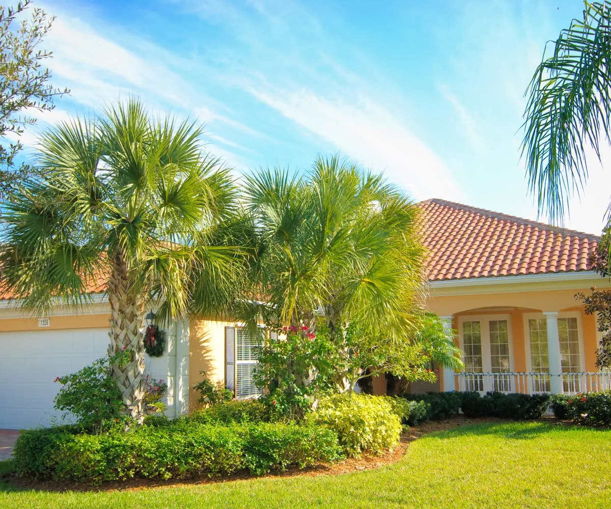 Tile-roofed home behind palms and tropical landscaping