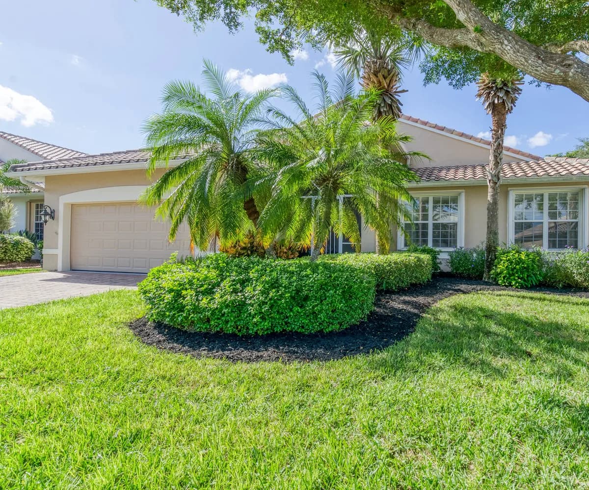 Stucco ranch home with a tile roof, palms and a live oak