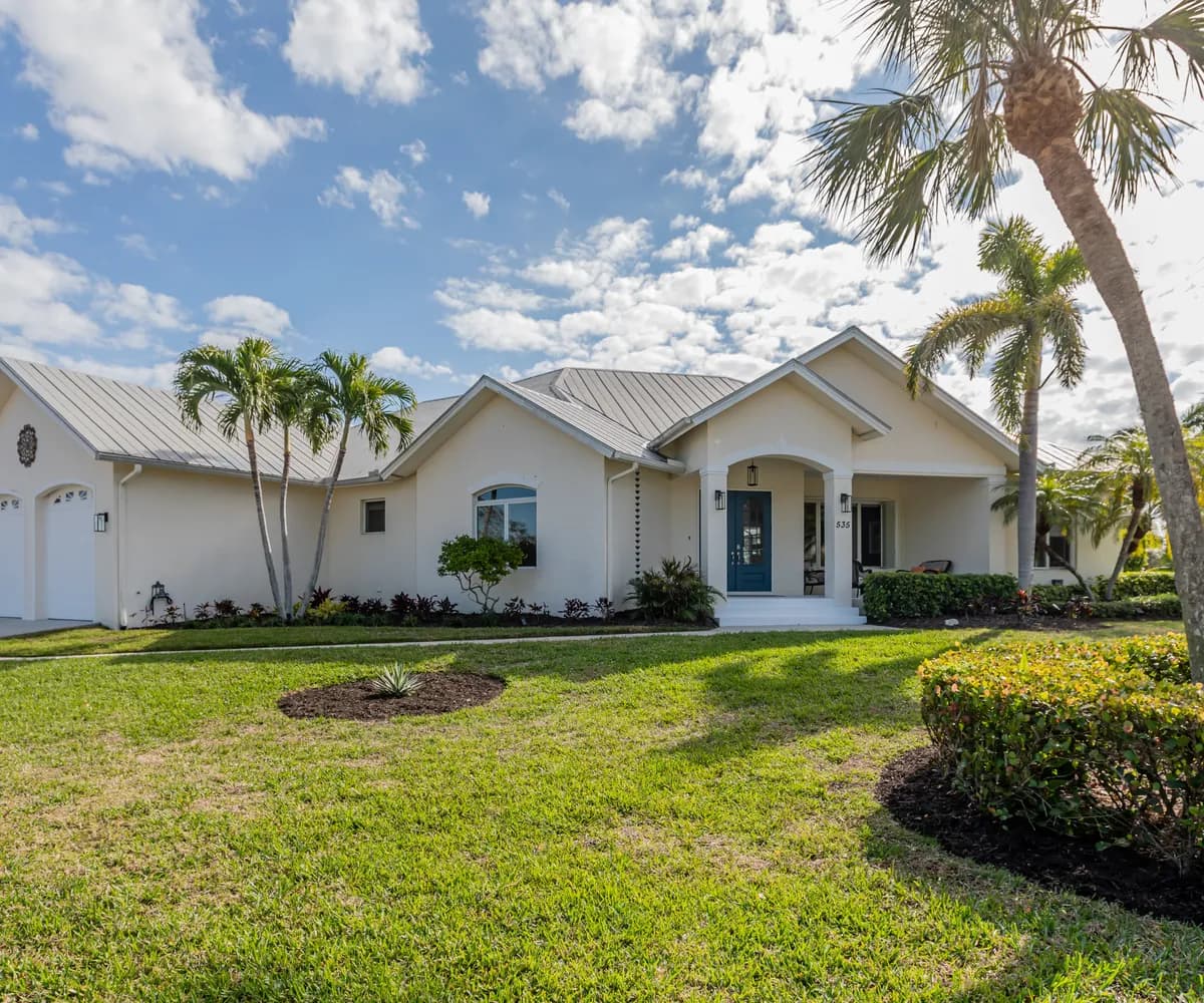 White home with a metal roof and palm trees